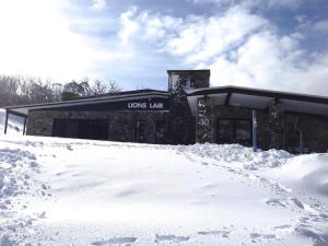 Smiggin Holes的住宿－The Lions Lair Lodge，前面有雪的建筑
