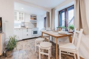 a white kitchen with a wooden table and chairs at Konekt Apartment in Český Krumlov