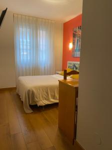 1 dormitorio con cama, escritorio y ventana en Hotel Costa Verde, en Gijón