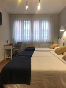 a bedroom with two large beds and a desk at Hotel Costa Verde in Gijón