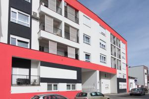 a red and white building with cars parked in front of it at Apartment Butterfly in Osijek
