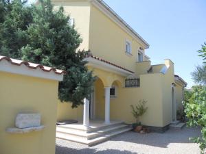 a large yellow house with a tree in front of it at Villa Rosana in Rab