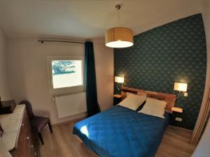 a bedroom with a blue bed and a window at chez anna in Montbrand