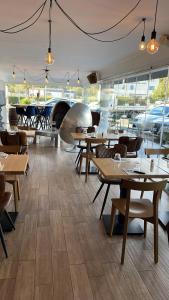 un restaurante con mesas y sillas de madera y ventanas en Hotel U Catagnu, en San-Nicolao