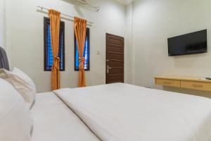 a bedroom with a white bed and two windows at Vandolia Guest House Medan RedPartner in Medan