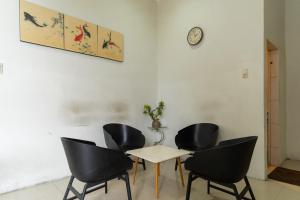 Habitación con 4 sillas, mesa y reloj en Vandolia Guest House Mitra RedDoorz, en Medan