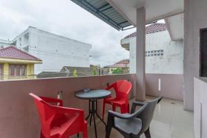 a patio with red chairs and a table on a balcony at Vandolia Guest House Medan RedPartner in Medan