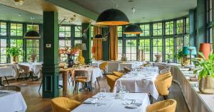 een restaurant met witte tafels, stoelen en ramen bij Restaurant & Hotel Hoog Holten in Holten