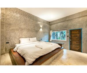 Cama grande en habitación con pared de piedra en Mac Garden Resort en Ban Phe