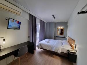 a bedroom with a bed and a desk and a window at Savoy Hotel in Piraeus