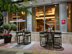 two tables and chairs in front of a store at Savoy Hotel in Piraeus
