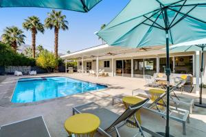 uma piscina com mesas e cadeiras e um guarda-sol em Serenity in Sunmor Permit# 4761 em Palm Springs