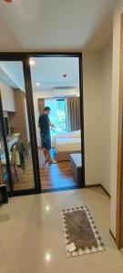 a person standing in a room with a bed and a mirror at Lahabana Huahin by Moji in Hua Hin