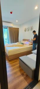 a man standing in a bedroom with two beds at Lahabana Huahin by Moji in Hua Hin