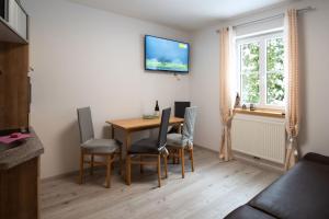 a dining room table with chairs and a television on the wall at Apartmenthaus HAUS Gipfelglück Apartment DOCHSTOA in Haus im Ennstal