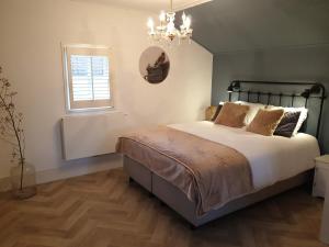 1 dormitorio con cama, ventana y lámpara de araña en Bed and Breakfast Warm Welkom, en Wezep