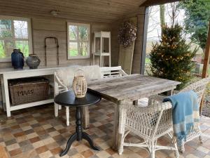 une table et des chaises en bois sur une terrasse couverte avec un arbre de Noël dans l'établissement Bed and Breakfast Warm Welkom, à Wezep