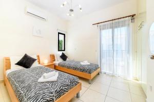 two beds in a room with a window at Protaras Centro Villa in Protaras