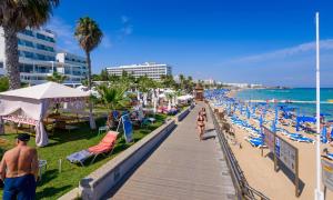 a beach with people walking down a boardwalk at Protaras Centro Villa in Protaras