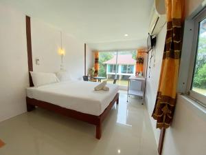 Un dormitorio con una cama grande y una ventana en Banpak Suankaew Talaynoi en Phatthalung