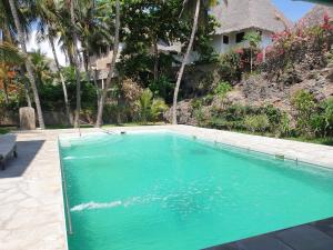 une piscine avec de l'eau bleue devant une maison dans l'établissement Marijani Holiday Resort, à Watamu