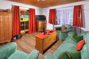 a living room with green furniture and red curtains at Hartlerlehen Rasp in Berchtesgaden