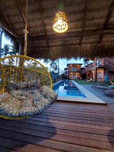 a swinging chair on a deck next to a swimming pool at Pousada Flor de Lena- Lotus in Icaraí