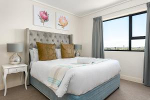 a white bedroom with a large bed and a window at Waters Edge Apartments in Cape Town