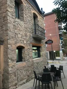 a stone building with tables and chairs in front of it at Albergue de Pas in El Pont de Suert