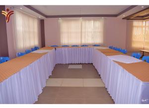 TRIPLINQ HOTEL & RESORT Meru في Nkubu: قاعة اجتماعات مع طاولات طويلة وكراسي زرقاء