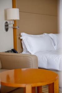 فندق كراون بلازا صحار في صحار: غرفة بها أريكة وسرير وطاولة