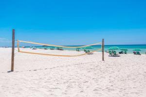 a volleyball net on a beach with chairs and umbrellas at Maravilla in Destin
