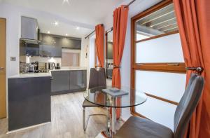 a dining room with a glass table and a kitchen at City Apartments - Reubens Court in York