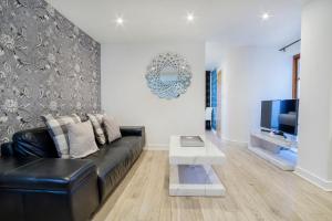 sala de estar con sofá de cuero negro y TV en City Apartments - Reubens Court, en York