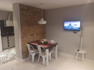 a dining room table with chairs and a television on a wall at Mieszkanie w Kamienicy 4C in Pasłęk