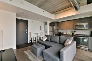 a living room with a couch and a kitchen at Cozy Skyline Condo in Downtown, across Canada Life Centre in Winnipeg