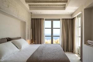 a bedroom with a bed and a large window at Verina Astra in Artemonas