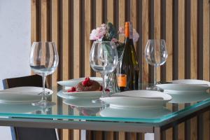 Lotniczówka Apartments by Renters Prestige في كراكوف: طاولة مع أطباق وأكواب وزجاجة من النبيذ
