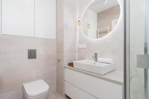 Baño blanco con lavabo y espejo en Lotniczówka Apartments by Renters Prestige, en Cracovia