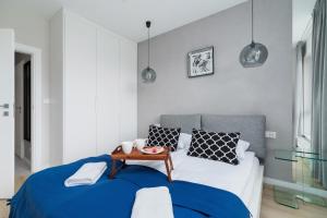 a bedroom with a bed with a blue blanket and a table at Lotniczówka Apartments by Renters Prestige in Kraków