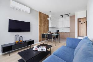 Lotniczówka Apartments by Renters Prestige في كراكوف: غرفة معيشة مع أريكة زرقاء وطاولة