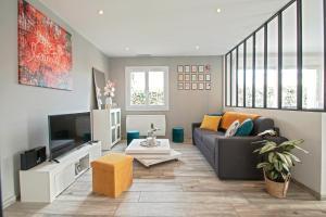 ein Wohnzimmer mit einem Sofa und einem TV in der Unterkunft Villa du soleil, piscine, à 10 mins de Montpellier in Vendargues