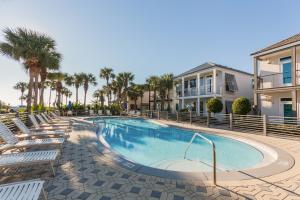 a swimming pool with chairs and palm trees at Destiny Beach Villa 11B in Destin