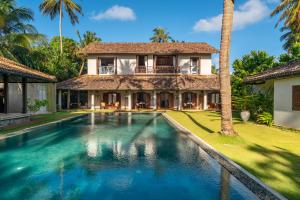 a villa with a swimming pool in front of a house at Sundara by Mosvold in Balapitiya