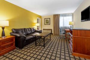 a living room with a leather couch and a table at Baymont by Wyndham Queensbury/Lake George in Queensbury