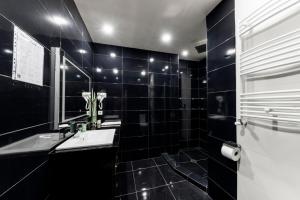 a black tiled bathroom with a sink and a mirror at Sani Apart Hotel in Tbilisi City
