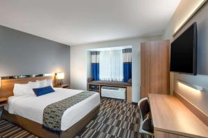 a hotel room with a bed and a flat screen tv at Microtel Inn & Suites by Wyndham Warsaw in Warsaw