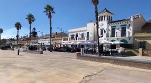 uma rua com mesas e guarda-sóis em frente a um edifício em Apartamento equipado playa Valencia OnesDeMar em Valência