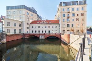 a bridge over a river in a city with buildings at Apartments Młyn Maria Wrocław by Renters in Wrocław