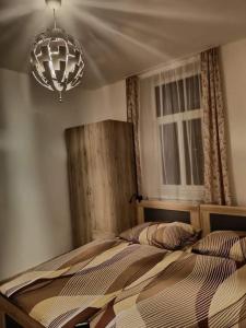 1 dormitorio con 1 cama con lámpara de araña y ventana en U pošty, en Albrechtice v Jizerských horách